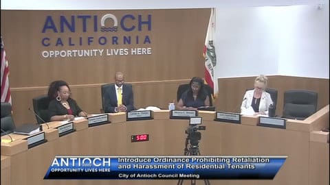 A black woman, a black man, a second black woman and white woman sitting in their city council seats during a meeting. Nameplates identify them as Tamisha Torres Walker, Lamar Thorpe, Monica Wilson and Lori Ogorchok. On the wall behind them, it says Antioch California Opportunity lives here. On screen text reads introduce ordinance prohibiting retaliation and harassment of residential tenants. City of Antioch council meeting