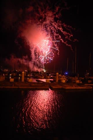 looking out over dark water toward red firework