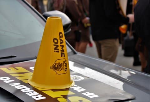 A yellow cone sound amplifier with writing that says "game on" and "UPS teamsters"