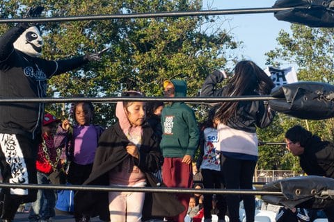 A man wearing a panda mask and several children in a wrestling ring