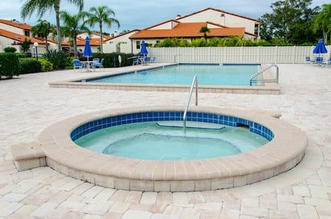 A hot tub with swimming pool in the background