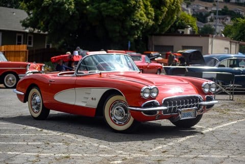 A classic red and white convertible with whitewall tires